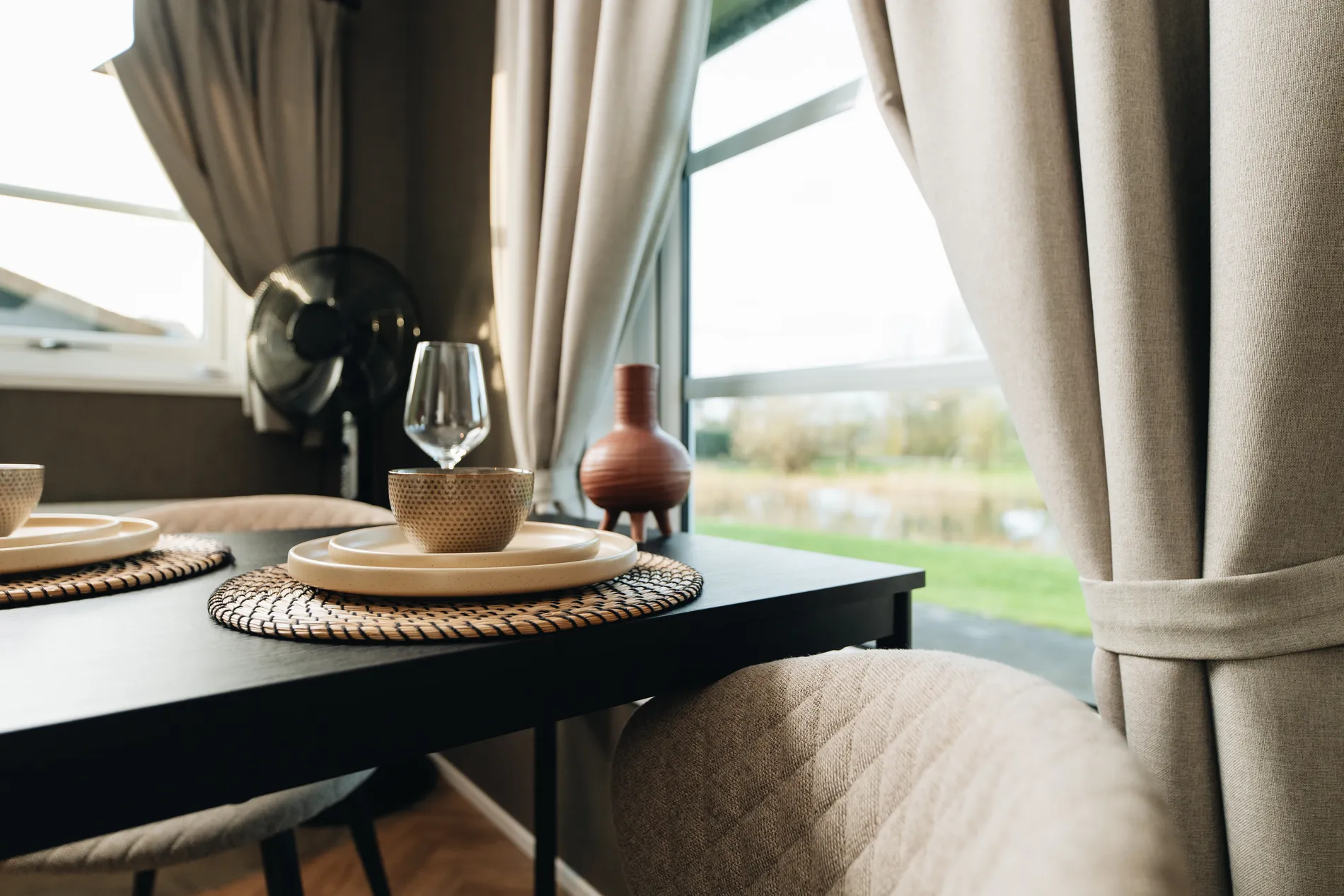 Detailopname van een gedekte tafel in een vakantiehuis, waarbij de focus ligt op de natuurlijke lichtinval en de serene sfeer van Resort Land & Zee.